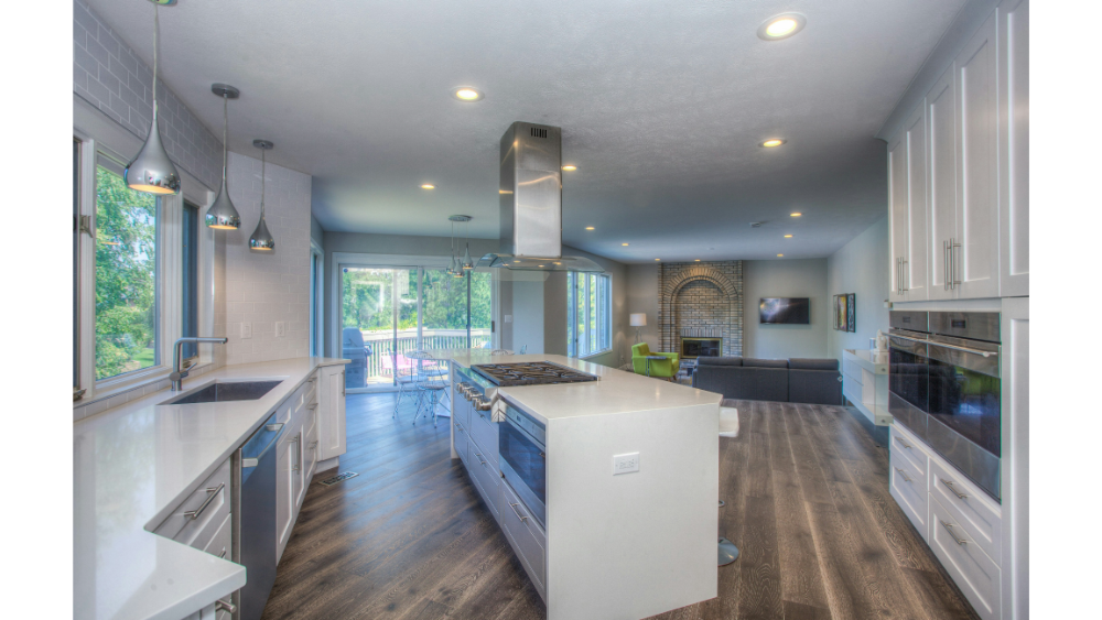 Open-Concept Kitchen With Dark Wood Floors, White Cabinetry, Modern Pendant Lights, And Large Windows Looking Out Onto A Green Backyard. Let Me Know If You Want These Optimized For Seo With Keyword Inclusion Or Styled For E-Commerce Platforms.