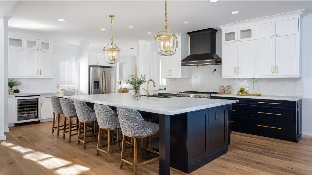 Modern Two-Tone Kitchen With White Upper Cabinets, Navy Blue Base Cabinets, Marble Countertops, And Gold Hardware And Fixtures.
