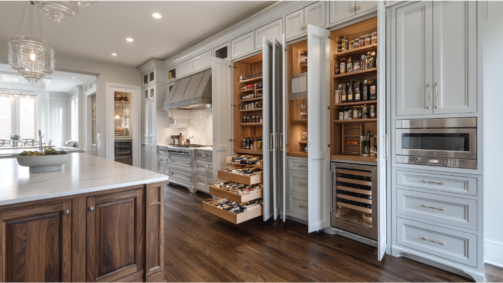Luxurious Kitchen With Light Gray Cabinets, A Hidden Pull-Out Pantry System, And Dark Hardwood Floors Creating A Classic And Functional Space.